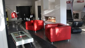 A modern living room with red sofas, a glass coffee table, and a fireplace.