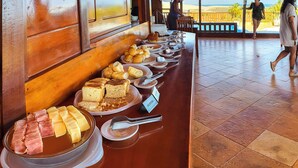 Una mesa de buffet con diferentes opciones de comida, incluyendo pasteles, productos de repostería y carnes.