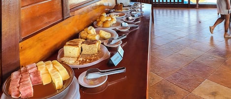 Une table de buffet proposant une variété de plats, notamment des gâteaux, des pâtisseries et des viandes.