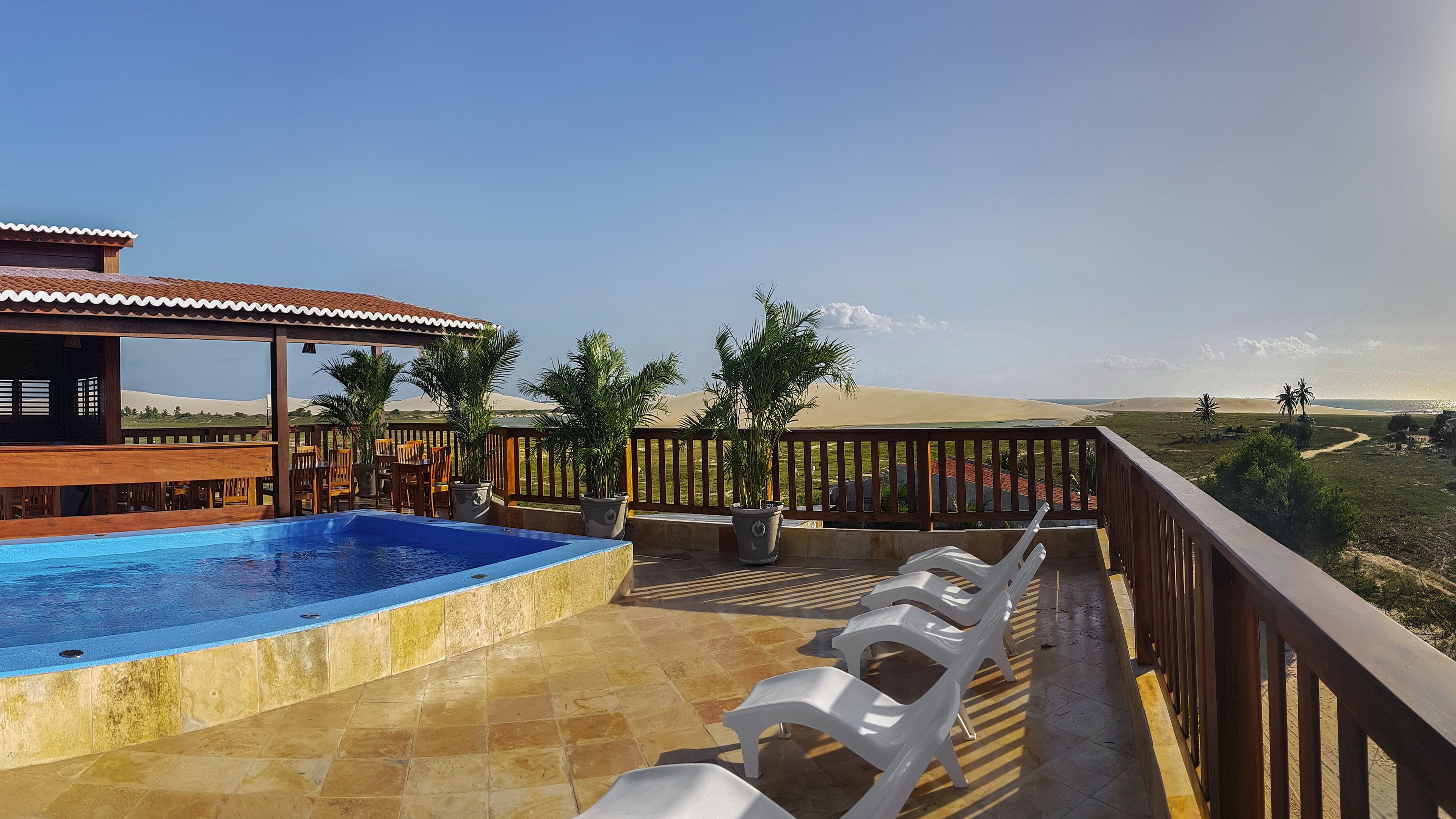 A rooftop pool area with a view of sand dunes and a clear sky.