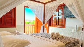 Un dormitorio con cama, cortinas blancas y vistas al exterior.