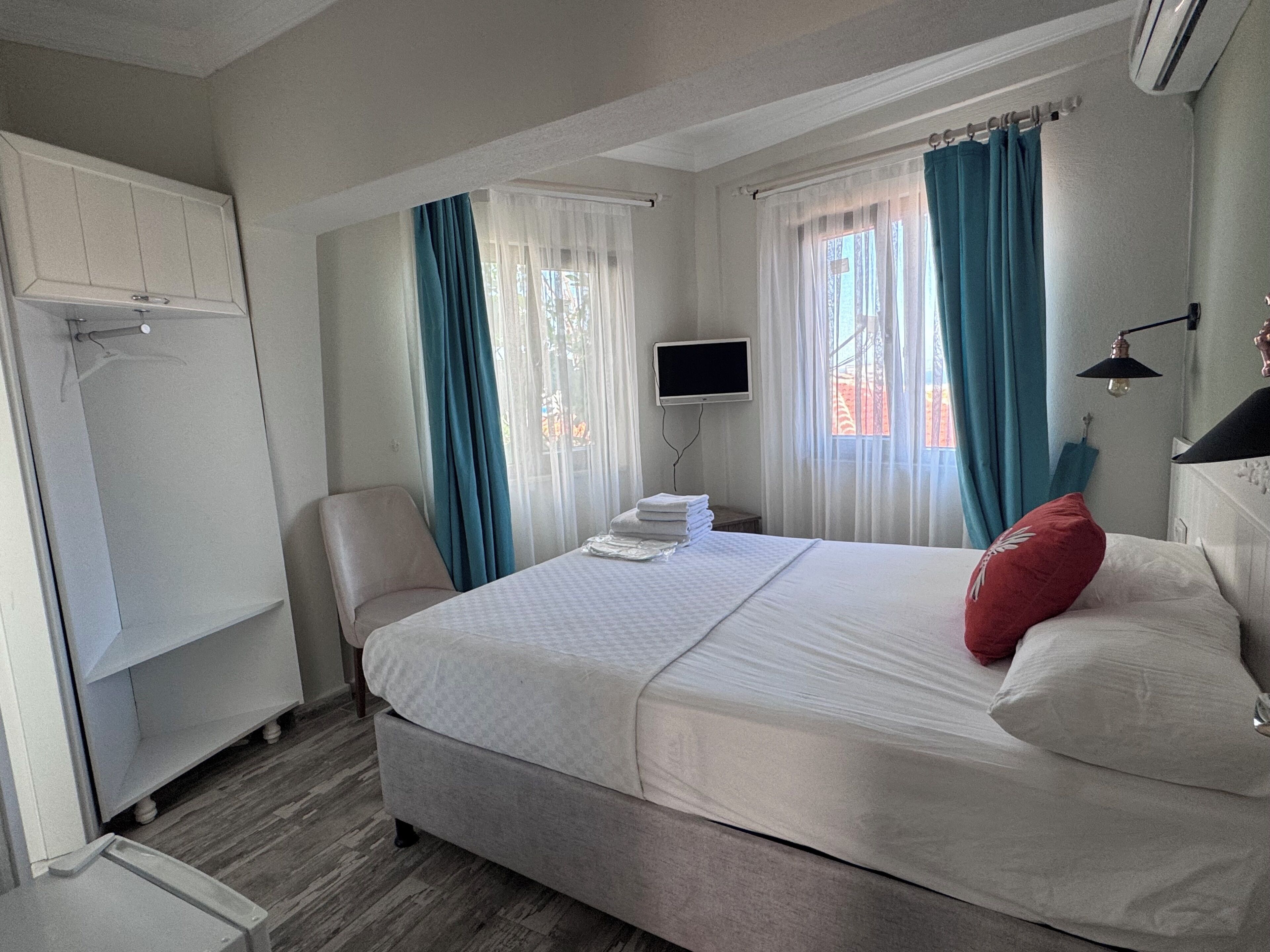 A bedroom with a bed, a television, a chair, and a wardrobe.