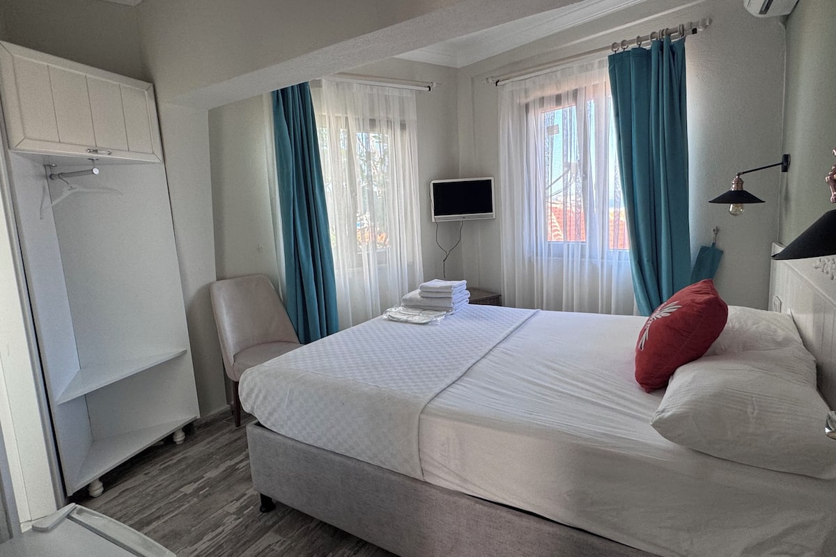 A bedroom with a bed, a television, a chair, and a wardrobe.