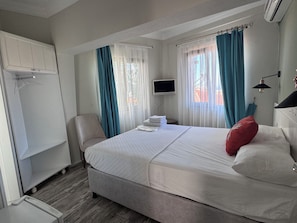 A bedroom with a bed, a television, a chair, and a wardrobe.