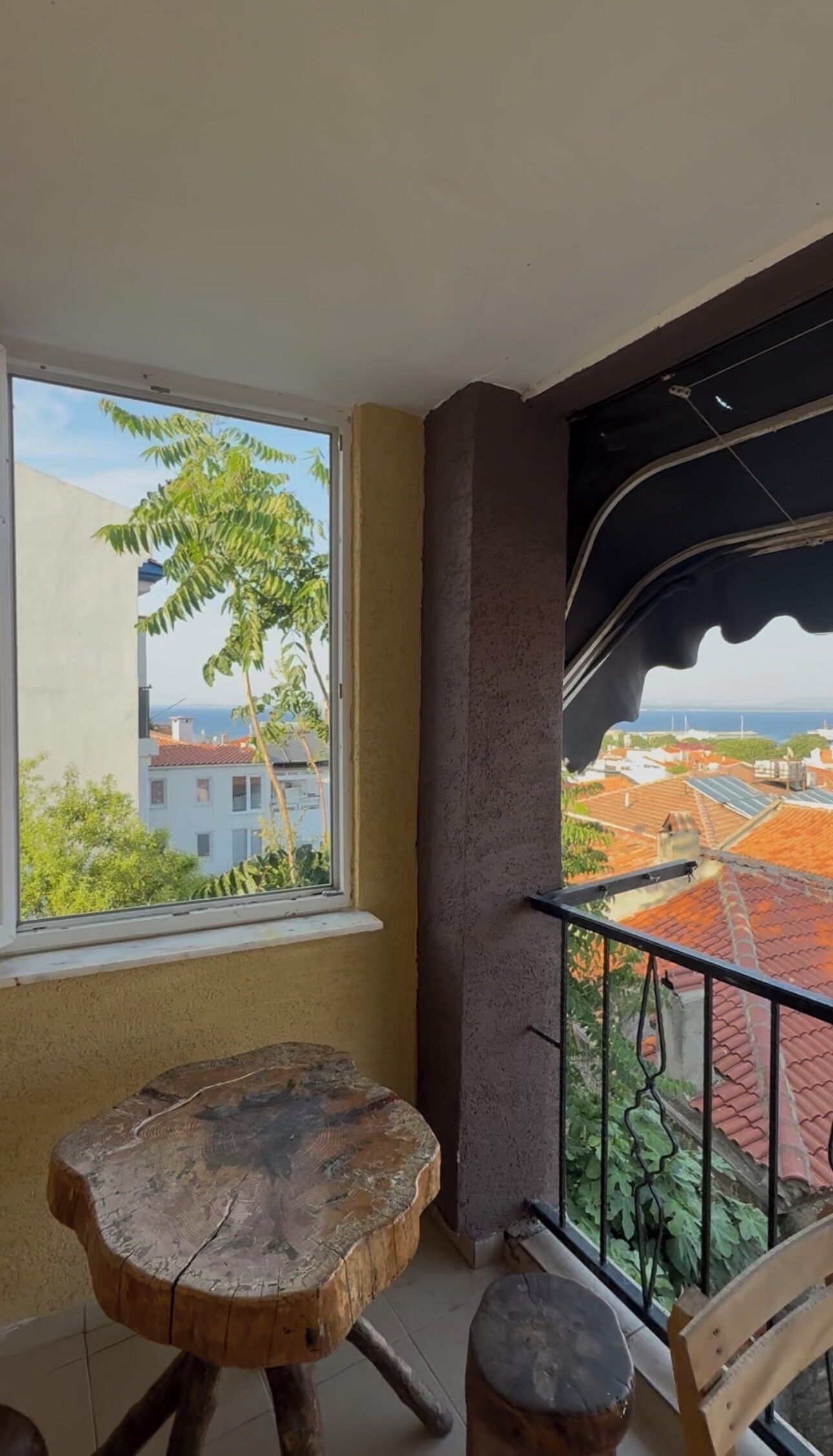 A balcony with a view of buildings and a tree.