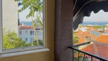 A balcony with a view of buildings and a tree.