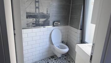 Un baño con inodoro blanco, lavamanos y zona de ducha.