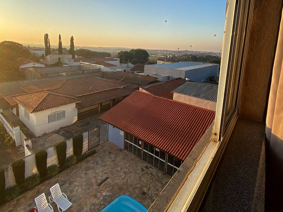 A view from a window overlooking a courtyard with a swimming pool, lounge chairs, and a red-tiled roof.
