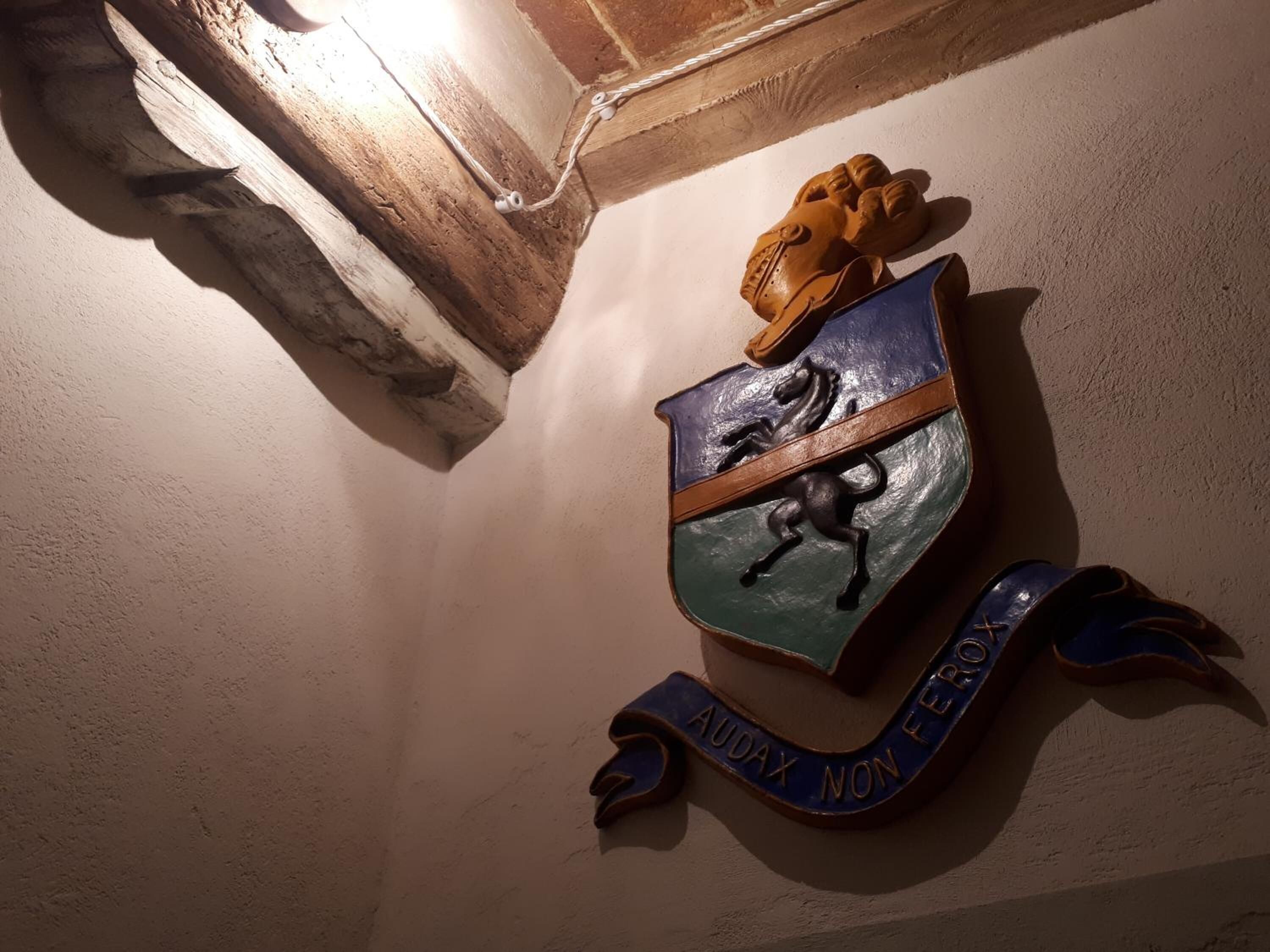 Um emblema fixado na parede com um escudo, um cavalo e uma bandeira.