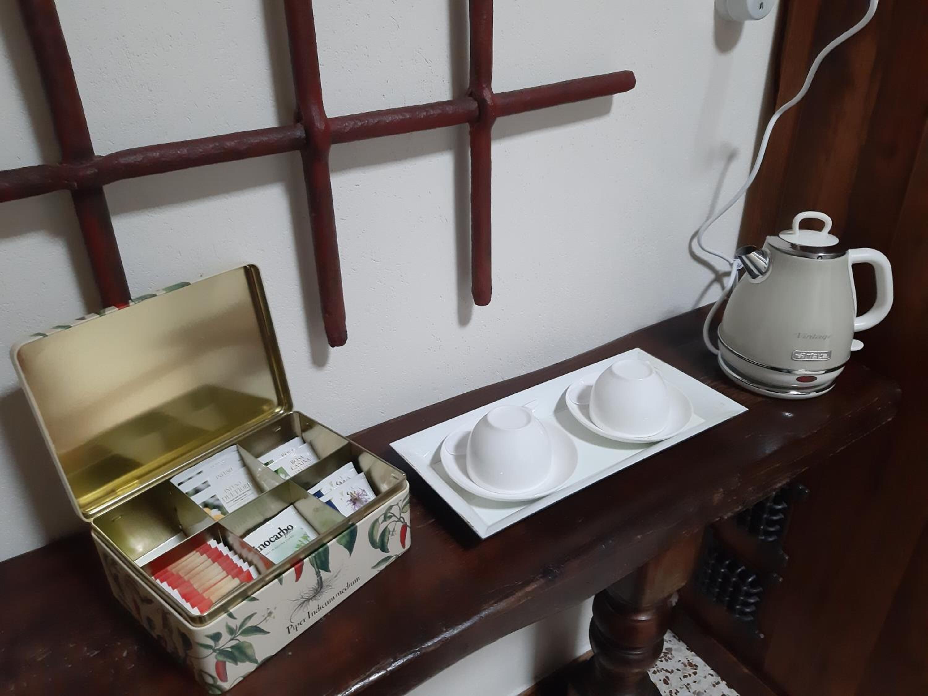 Una mesa de madera con un hervidor blanco, una lata de té y dos tazas blancas sobre una bandeja.