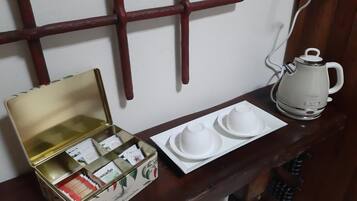 Una mesa de madera con un hervidor blanco, una lata de té y dos tazas blancas sobre una bandeja.