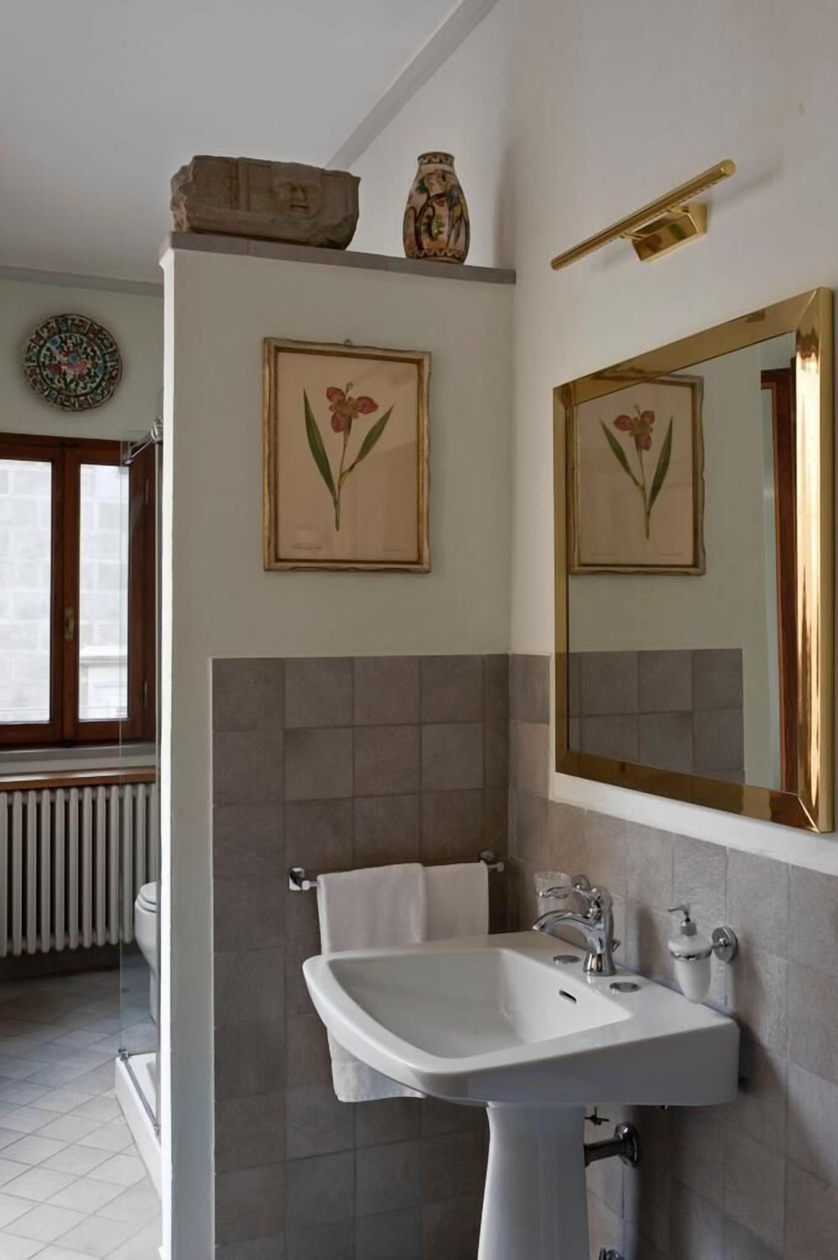 A bathroom with a white sink, a mirror, and framed botanical prints on the wall.