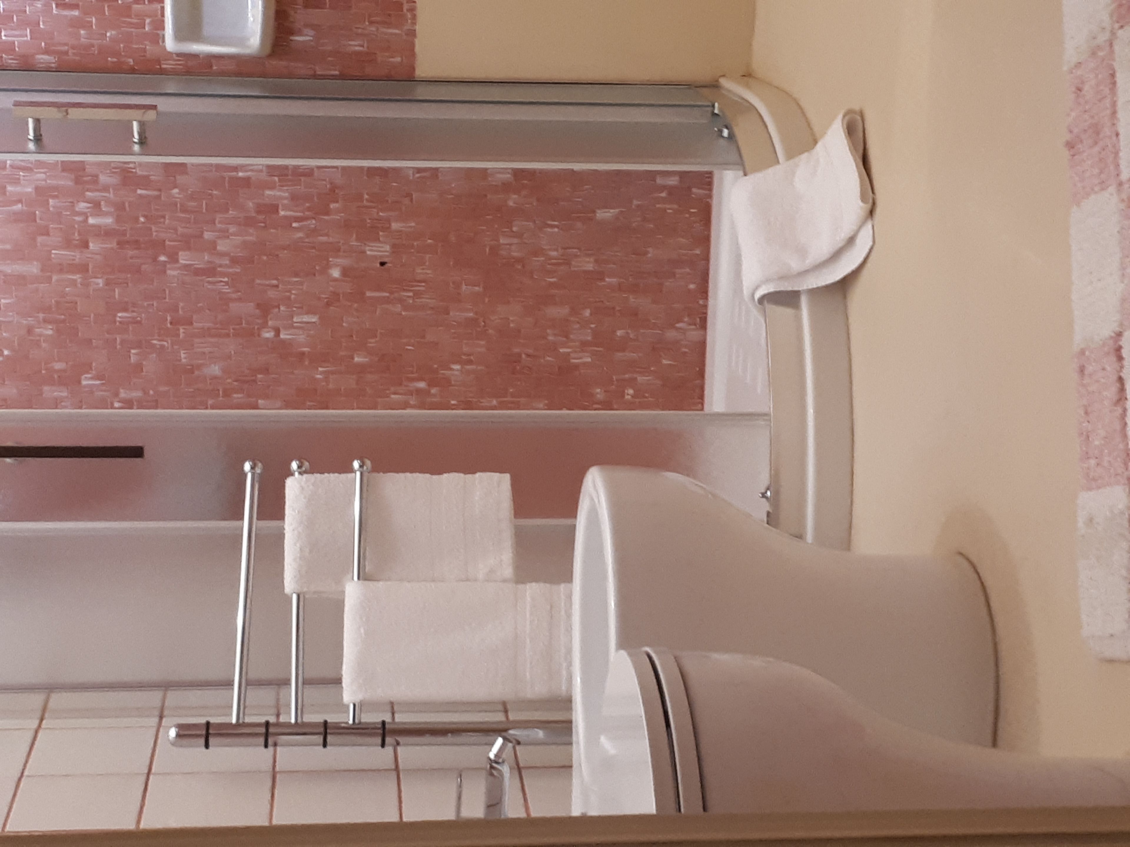 A bathroom with a bathtub, a towel rack, and a mirror.