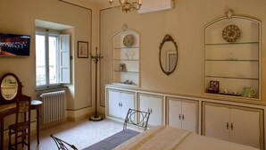 A bedroom with a bed, a dresser, a mirror, and a television. - Dolce Rosa  Centro Storico (Sansepolcro)