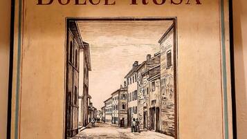 Uma placa emoldurada com 'B&B Dolce Rosa' e uma ilustração de uma cena de rua.