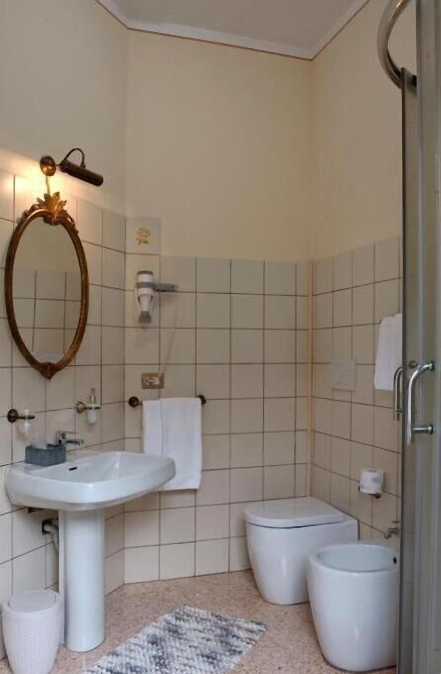 Un baño con lavamanos pedestal, espejo, toallero, inodoro y bidé.