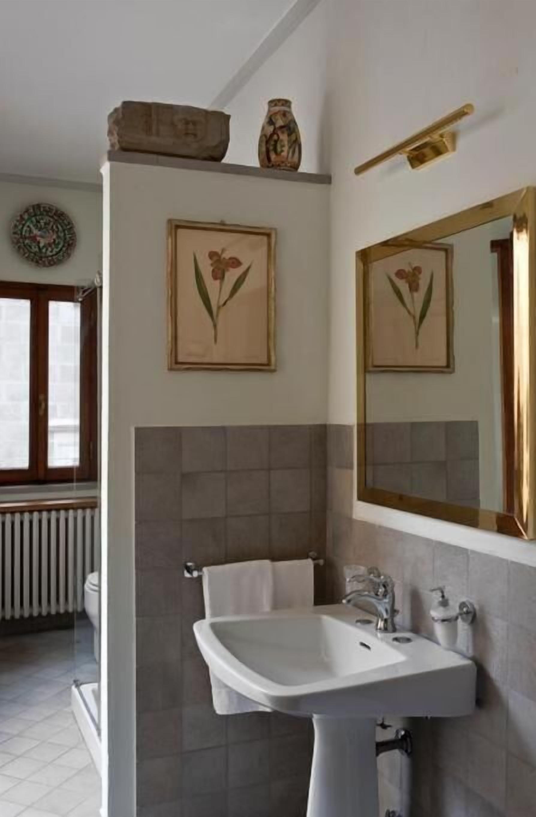 A bathroom with a white sink, a towel rack, and two framed floral paintings on the wall.