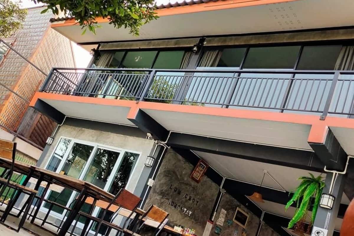 Ein zweistöckiges Gebäude mit Balkon, Außenbereich zum Sitzen und einem Schild mit der Aufschrift 'LOW COST HONESTY'.