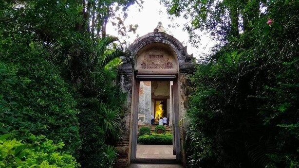 A temple entrance with a Buddha statue, surrounded by lush greenery. - Lom Choi Home Stay Ayutthaya - Hostel (Ayutthaya)