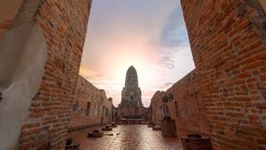 A brick pathway leading to a large, ornate building with a central spire, framed by brick walls. - Lom Choi Home Stay Ayutthaya - Hostel (Ayutthaya)