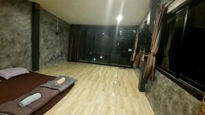 A room with a bed, a massage table, a large window, and a view of the outside. - Lom Choi Home Stay Ayutthaya - Hostel (Ayutthaya)
