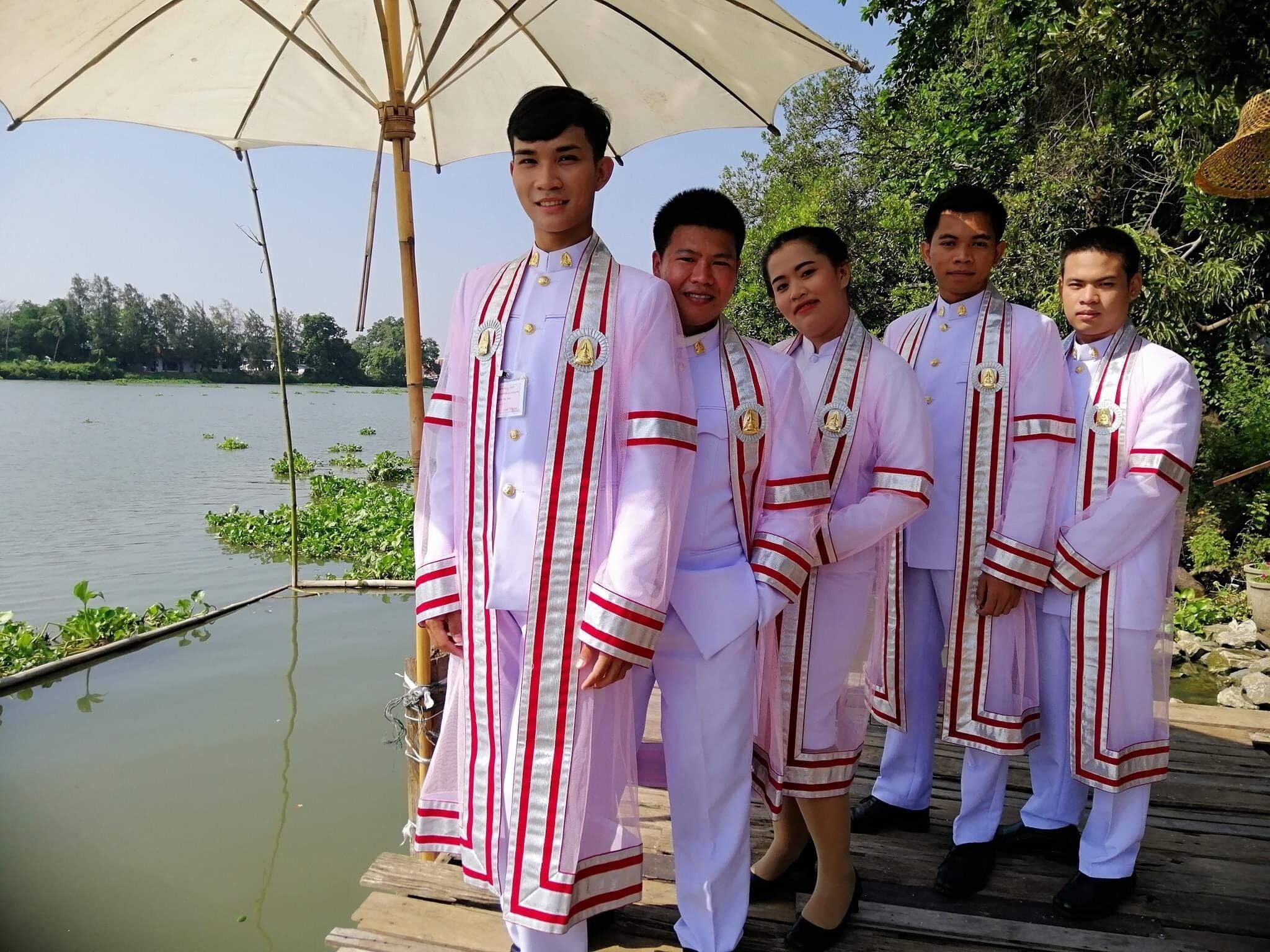 Un grupo de personas vestidas con traje tradicional sobre un muelle de madera junto a un lago.
