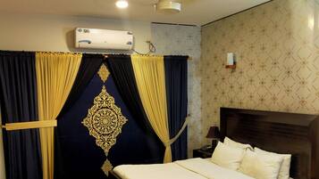 Un dormitorio con cama, cortinas, ventilador de techo, aire acondicionado y pared con diseño.