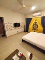 Habitación de hotel con cama, televisión de pantalla plana montada en la pared, aire acondicionado y pared decorada.
