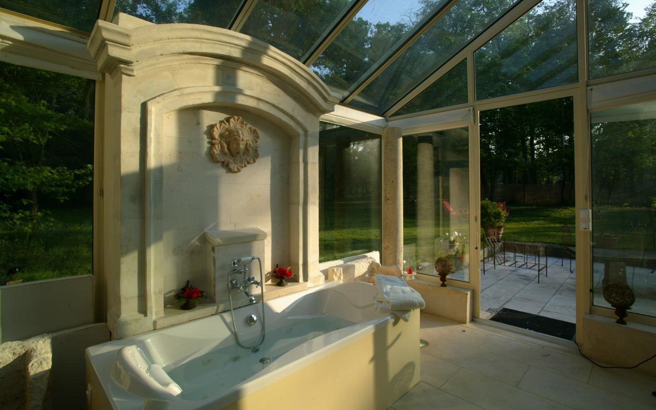 A spa area with a large bathtub, a shower, and a glass-enclosed patio with a view of the garden.