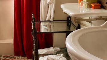 A bathroom with a bathtub, a sink, and a mirror. There are towels hanging on a rack, and a window with red curtains.
