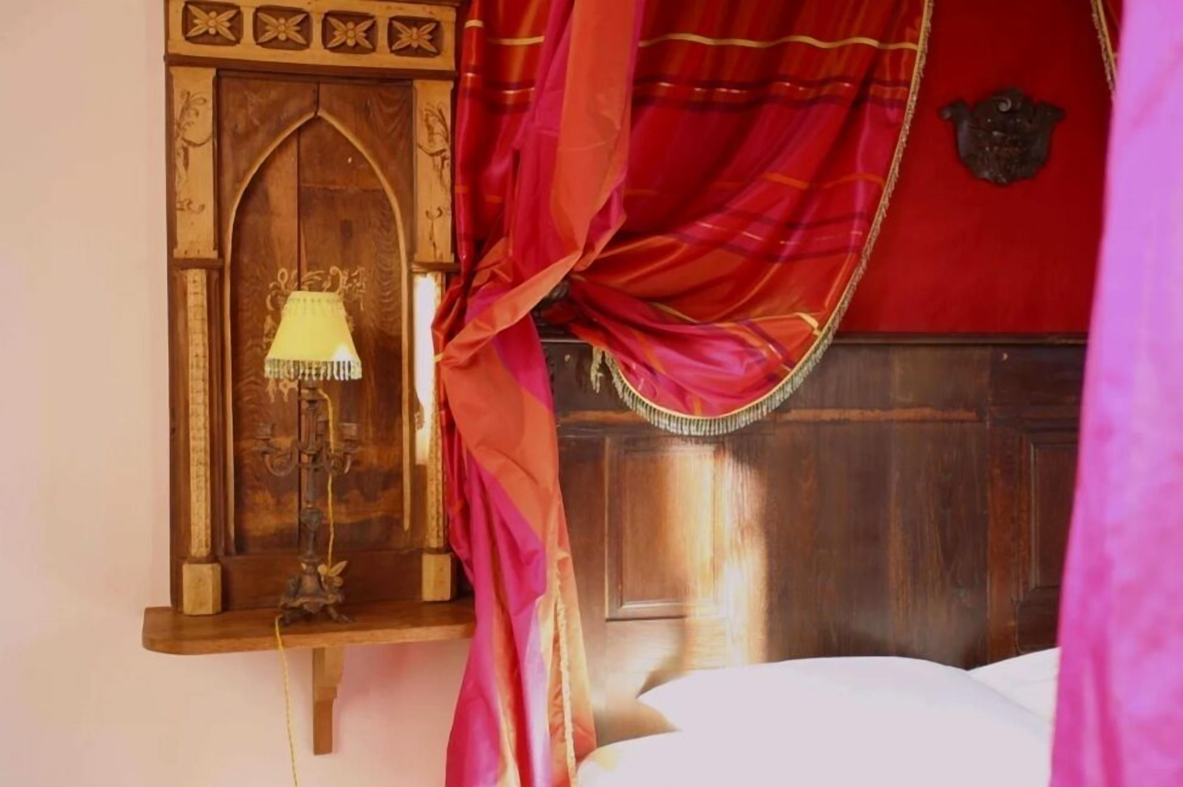 Een kamer met een houten hoofdbord, een bed met witte beddengoed en een lamp op een bijzettafeltje.