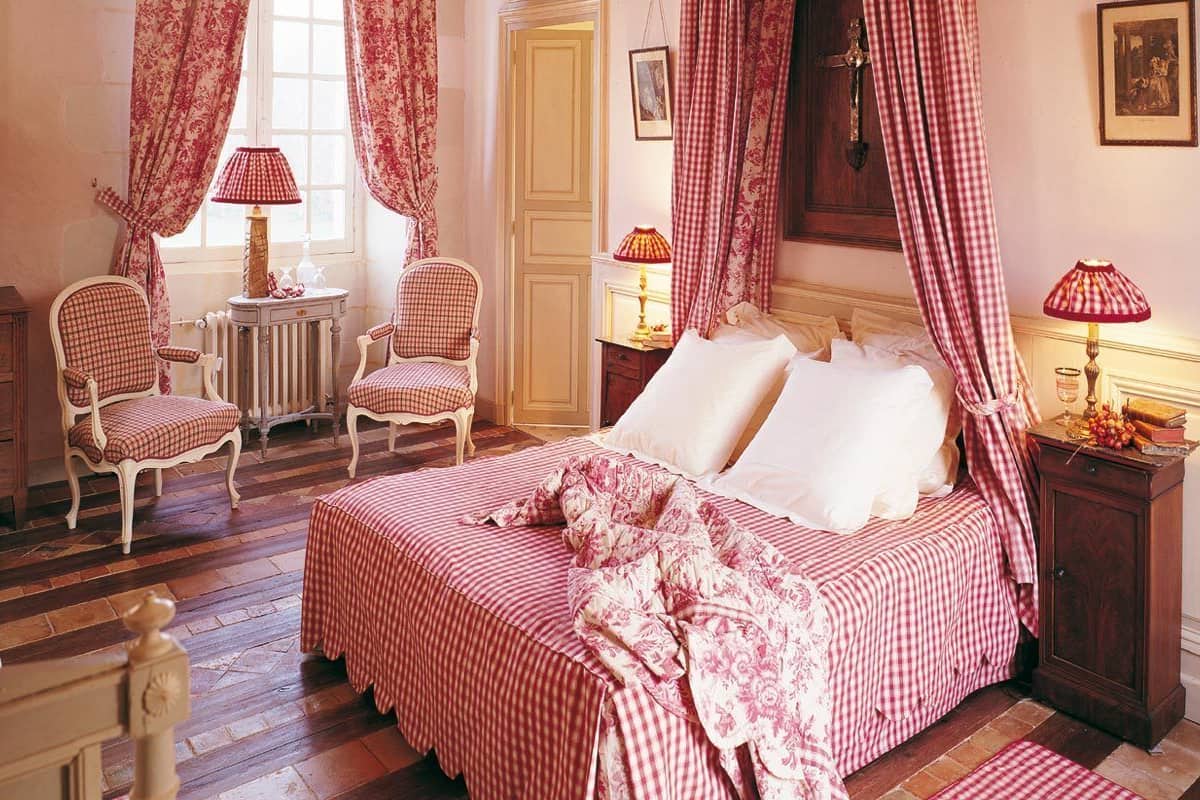 Une chambre à coucher avec un lit à baldaquin, deux chaises, une petite table et un buffet.