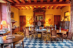 Comedor con piso a cuadros, muebles de madera y chimenea en el centro.
