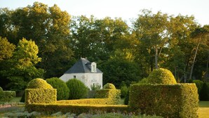 Un bâtiment historique entouré de jardins bien entretenus et d’une végétation luxuriante.