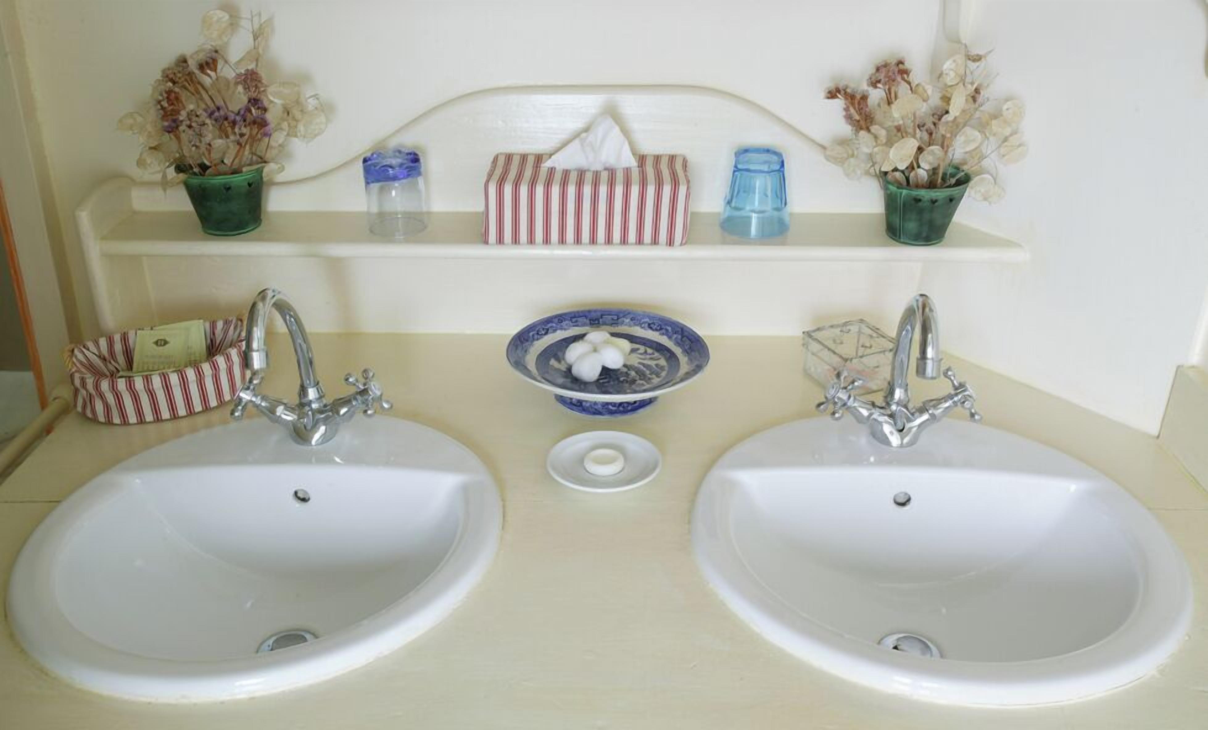 A bathroom with two sinks, a mirror, and shelves with toiletries.