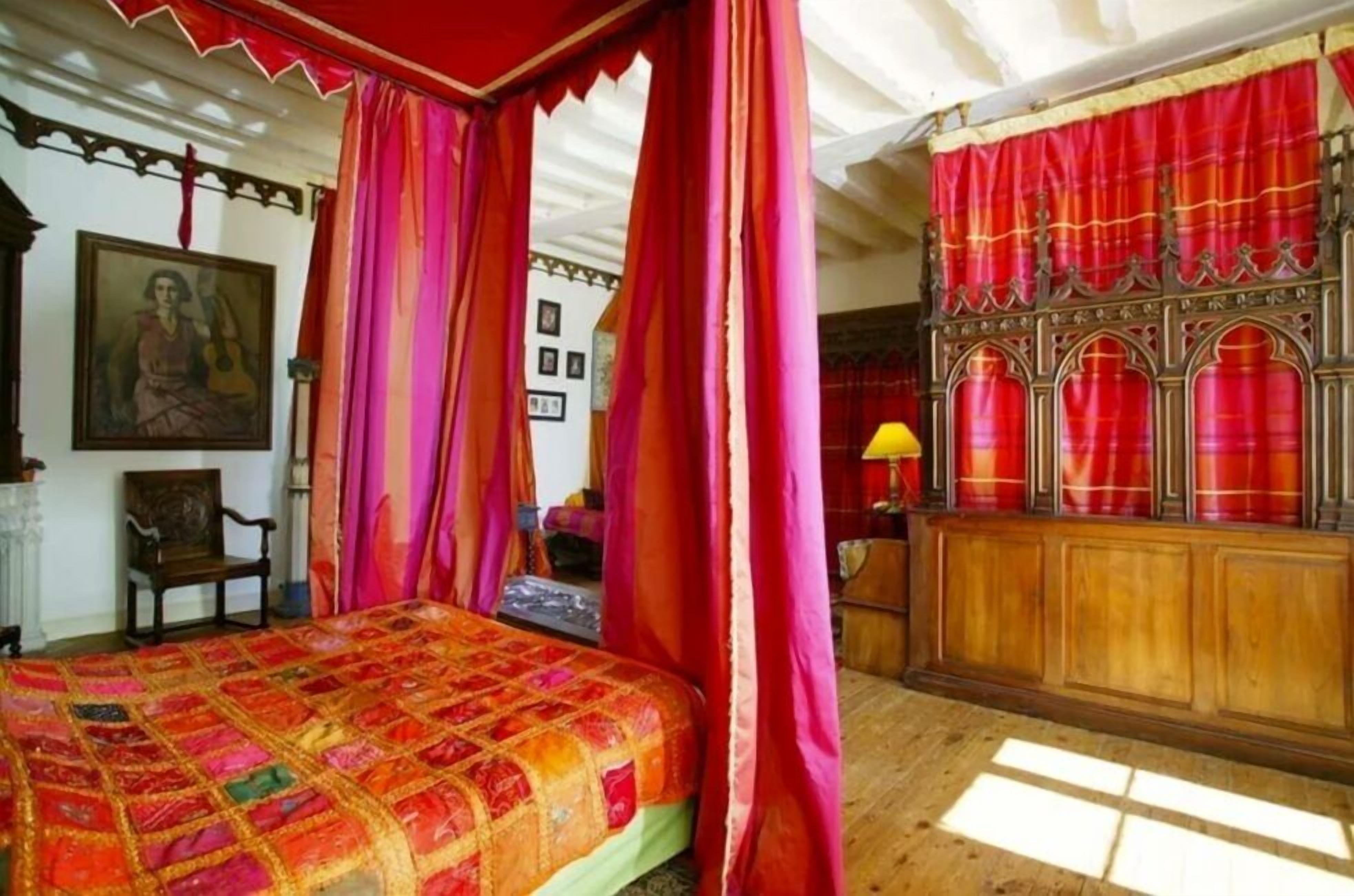A room with a bed, a wooden cabinet, and a red curtain.