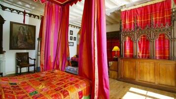 A room with a bed, a wooden cabinet, and a red curtain.
