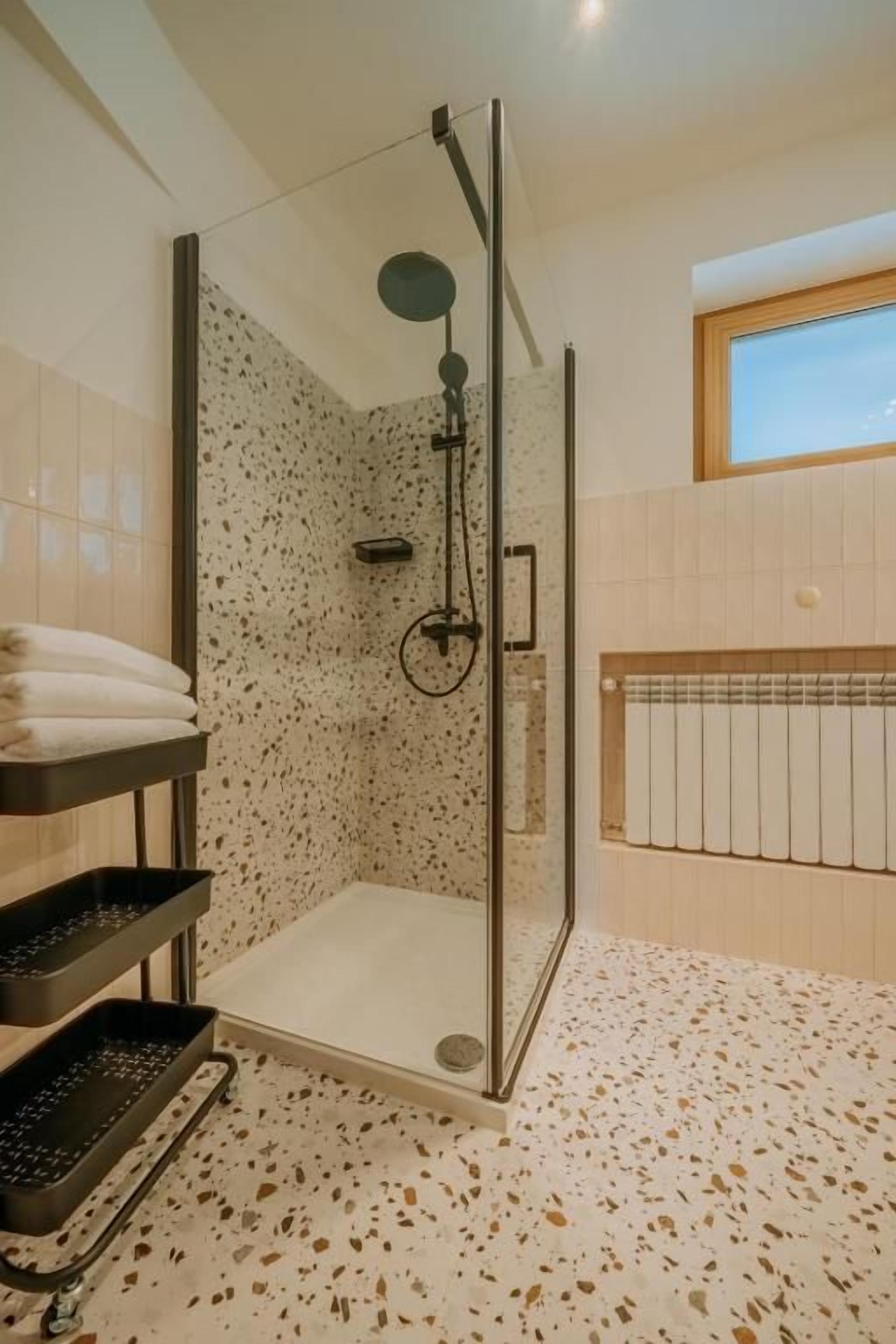 A modern shower area with a glass enclosure, a built-in bench, and a tiled floor.