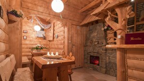 A cozy wooden interior with a dining table, benches, a fireplace, and a stone wall. - Dom Wypoczynkowy U Staszla (Szaflary)