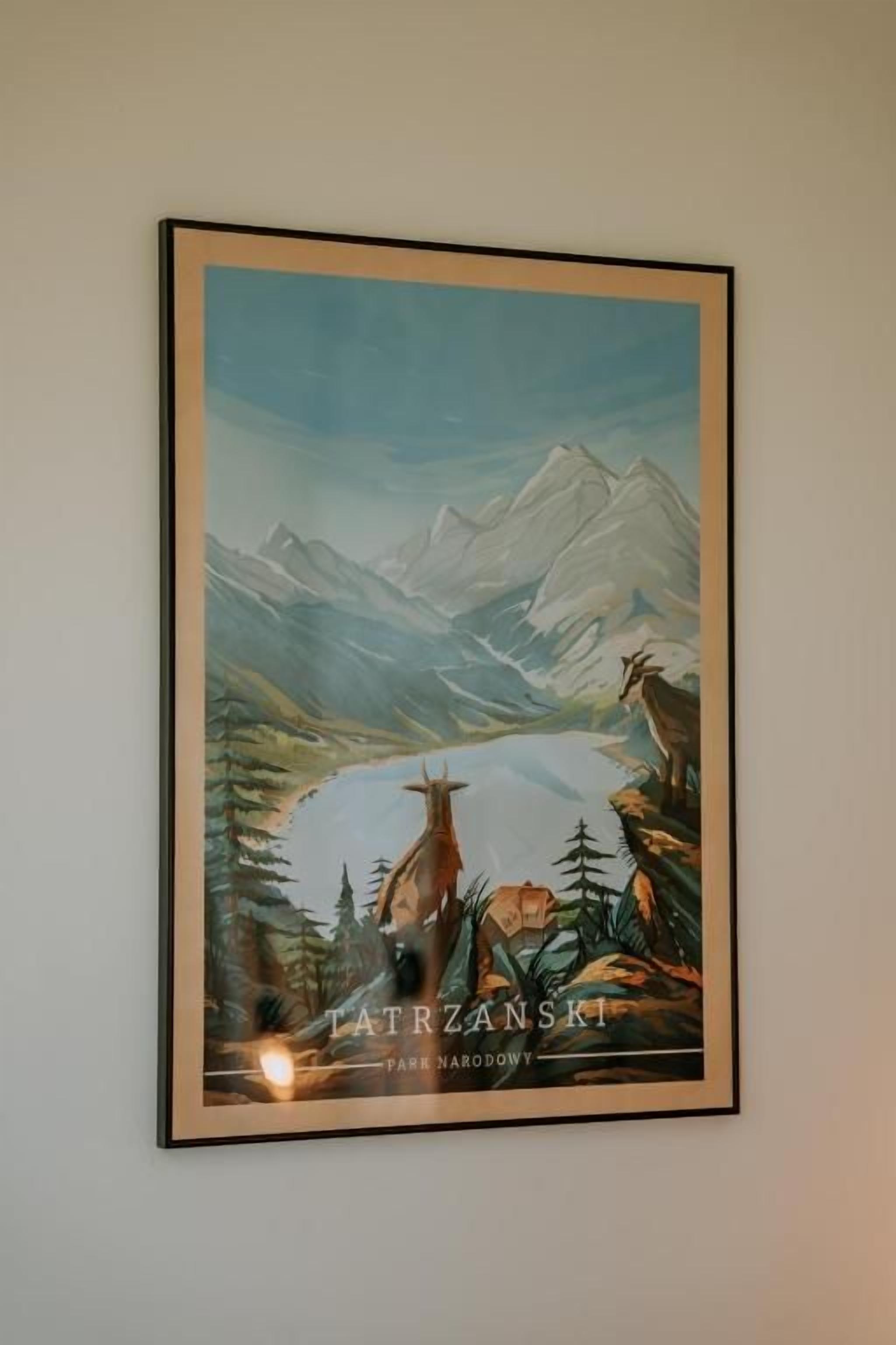 Une peinture représentant un paysage de montagne encadrée, avec un lac et des animaux sauvages, et intitulée « Parc national des Tatras ».