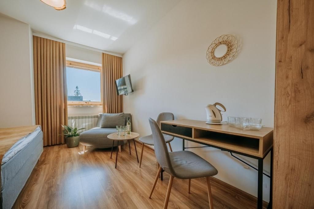Un espace de vie compact comprenant un canapé, une petite table, un bureau et un téléviseur fixé au mur.