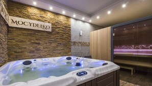 A spa area with a hot tub, stone wall, wooden paneling, and a bench. - Dom Wypoczynkowy U Staszla (Szaflary)