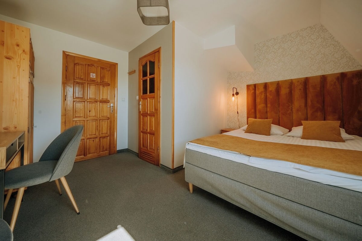 A bedroom with a bed, a desk, and two doors.