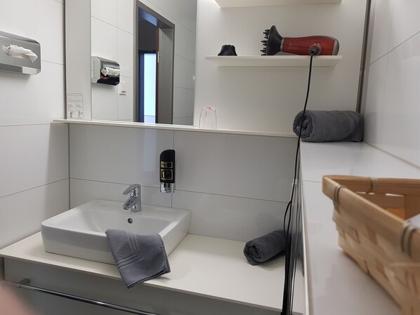 Un baño moderno con un lavamanos blanco, un espejo y un perchero para toallas.