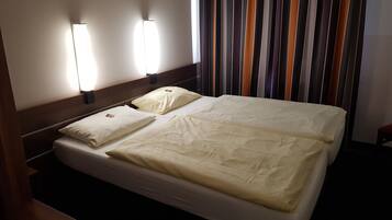 Una habitación de hotel con una cama, dos lámparas de noche y una cortina a rayas.