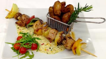 Une assiette de brochettes de poulet grillées, de pommes de terre rôties et d’une sauce crémeuse aux légumes.