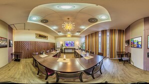 Uma sala de conferências com uma grande mesa redonda, cadeiras, uma tela de TV e obras de arte nas paredes.
