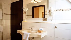 Un baño con lavamanos, espejo y toallero.