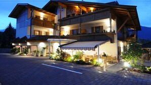 Un hotel de varios pisos con una zona de estar cubierta al aire libre, varios balcones y una entrada bien iluminada.