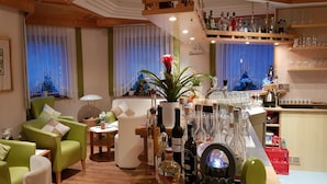 Una sala de estar acogedora con sofás verdes, una mesa de centro y una zona de bar con varias botellas y copas.
